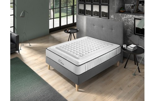 Colchón Kalma blanco con acolchado, sobre base gris en dormitorio moderno con luz natural