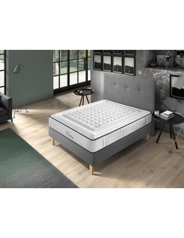 Colchón Kalma blanco con acolchado, sobre base gris en dormitorio moderno con luz natural