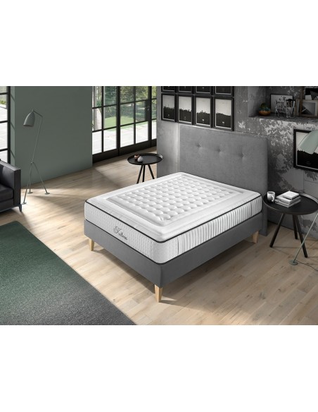 Colchón Kalma blanco con acolchado, sobre base gris en dormitorio moderno con luz natural